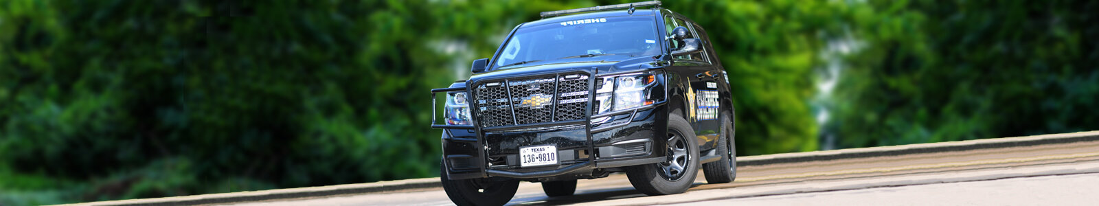 A single Kleberg County Sheriff’s Office patrol SUV parked in front of a green forest background.